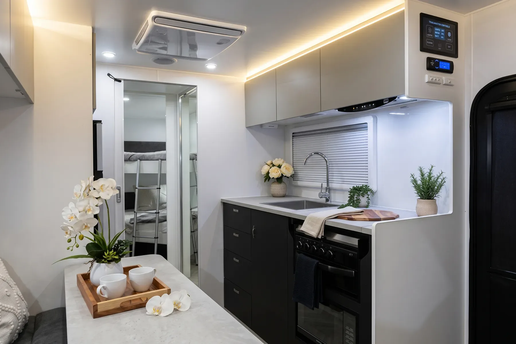 Caravan interior looking toward the bed: CNC cabinetry, waterfall benchtop and floor, bush through the windows